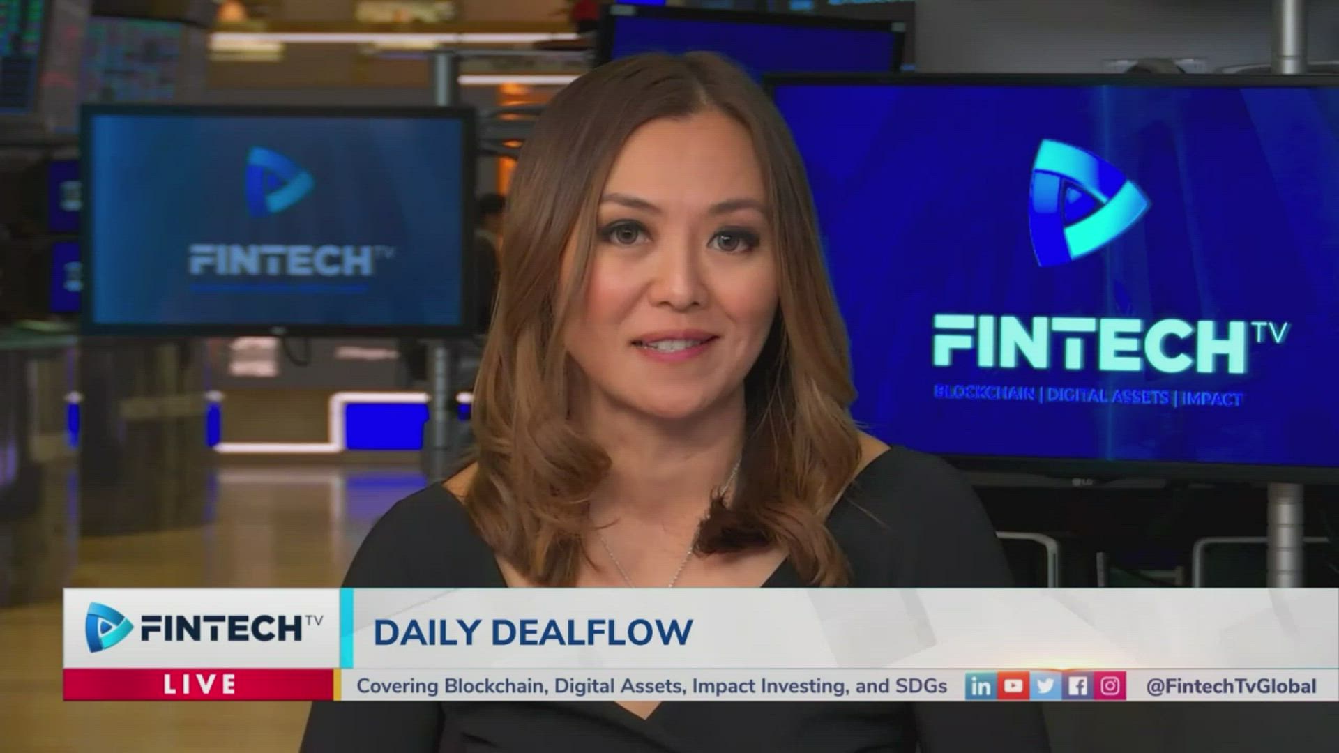 News anchor with brown hair in a black top in a Fintech TV studio, blue screens display FINTECH branding behind her, with a Daily DealFlow banner on the ticker